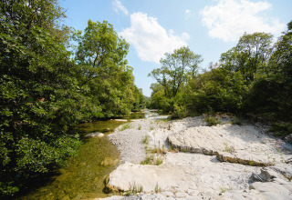 Uitzicht bij Medrose Camping in Auvergne-Rhône-Alpes, Frankrijk, met rivier, rotsen en bomen onder een blauwe hemel.