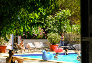 Ferienpark Medrose Camping in Auvergne-Rhône-Alpes mit Menschen am Pool und vielen Bäumen im Hintergrund.