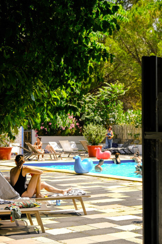 Ferienpark Medrose Camping in Auvergne-Rhône-Alpes mit Menschen am Pool und vielen Bäumen im Hintergrund.