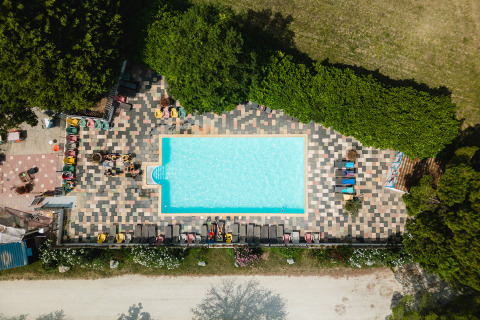 Vista aerea di piscina circondata da lettini colorati e alberi a Medrose Camping, Auvergne-Rhône-Alpes, Francia.