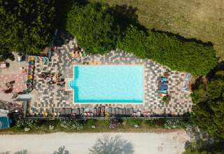 Draufsicht auf einen Pool mit bunten Liegestühlen und Bäumen bei Medrose Camping in Auvergne-Rhône-Alpes.