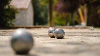 Bolas metálicas de petanca sobre grava en Medrose Camping, Auvergne-Rhône-Alpes, Francia, fondo desenfocado.