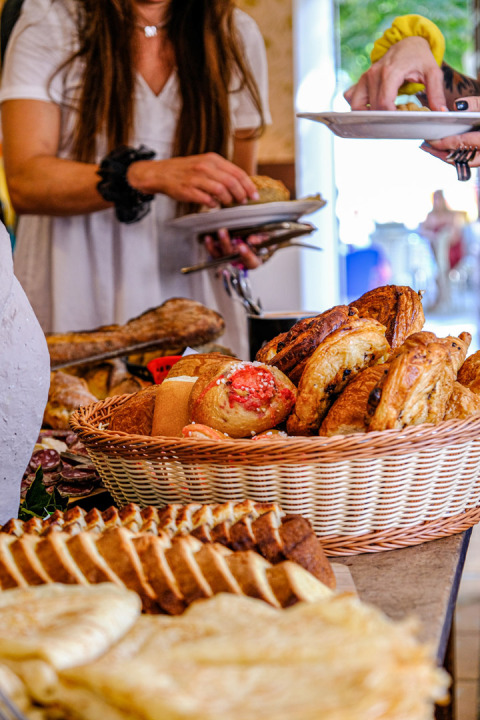 Mesa buffet con pasteles y pan fresco, huéspedes sirviéndose comida en Medrose Camping en Francia.