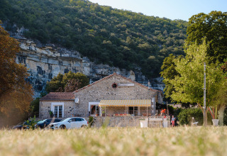 Edificio in pietra al Medrose Camping con montagne e alberi in Auvergne-Rhône-Alpes, Francia, giornata di sole