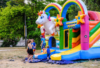Kinder spielen auf einer bunten Einhorn-Hüpfburg im Medrose Camping, Auvergne-Rhône-Alpes, Frankreich.