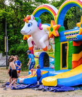 Niños juegan en un colorido castillo hinchable de unicornio en Medrose Camping, Auvernia-Ródano-Alpes, Francia.