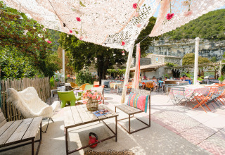 Buitenlounge bij Medrose Camping in Auvergne-Rhône-Alpes, Frankrijk, met kleurrijke stoelen en bloemen.