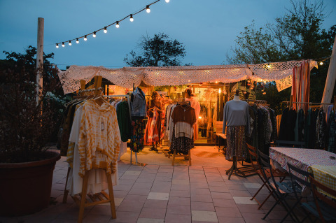 Stand de vêtements éclairé en plein air au crépuscule à Medrose Camping, Auvergne-Rhône-Alpes, France.