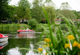 Jongen geniet in een bootje op een vijver omringd door natuur in Parc de Witte Vennen, Limburg.