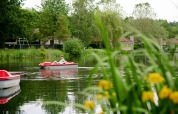 Boy relaxing in a rowboat on a serene lake surrounded by greenery at Parc de Witte Vennen holiday park.