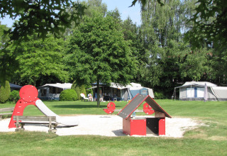 Spielplatz auf einem Campingplatz im Parc de Witte Vennen, Limburg, Niederlande mit Zelten im Hintergrund.