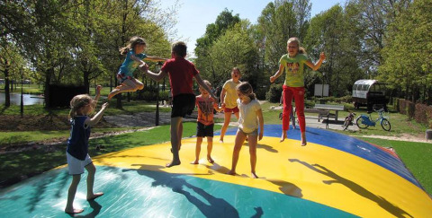 Niños saltando y jugando sobre un gran cojín inflable en Parc de Witte Vennen, Limburg, Países Bajos.