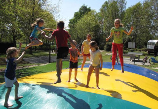 Bambini che saltano e giocano su un grande cuscino gonfiabile al Parc de Witte Vennen, Limburgo, Paesi Bassi.