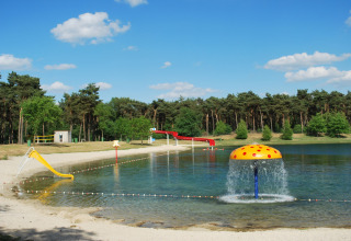 Speelvijver in Parc de Witte Vennen met glijbaan, paddenstoel fontein en zandstrand in Limburg, Nederland.