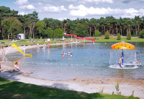 Bambini giocano in un lago poco profondo con scivoli e giochi d'acqua a Parc de Witte Vennen, Limburgo, Paesi Bassi.
