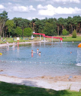 Niños juegan en un lago poco profundo con toboganes y juegos acuáticos en Parc de Witte Vennen, Limburg, Holanda.