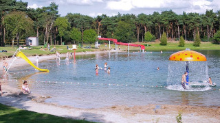 Niños juegan en un lago poco profundo con toboganes y juegos acuáticos en Parc de Witte Vennen, Limburg, Holanda.
