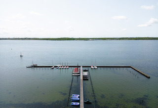 Luftfoto af bådebro og små både ved RCN de Schotsman feriepark i Zeeland, Holland, med roligt vand.