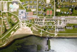 Luchtfoto van RCN de Schotsman, een vakantiepark in Zeeland, Nederland, met strand, huisjes en haven.