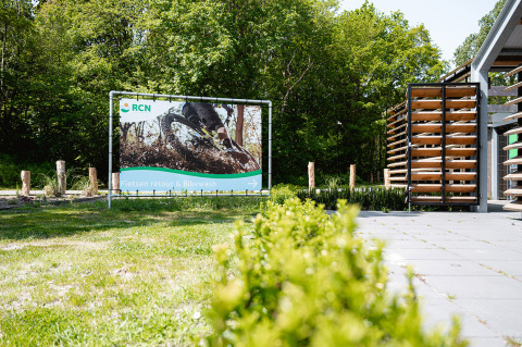 Cartel de RCN de Schotsman junto a soportes para bicicletas en el parque vacacional de Zeeland, Países Bajos.
