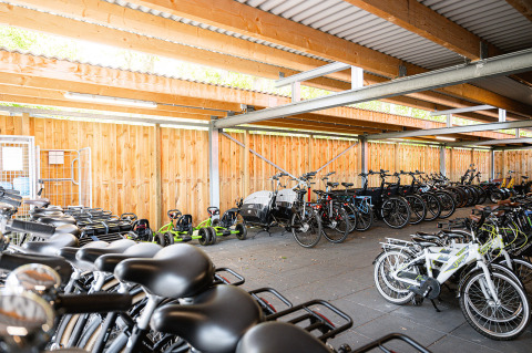 Aparcamiento cubierto de bicicletas con muchas bicicletas y karts en el parque vacacional RCN de Schotsman, Zeeland.
