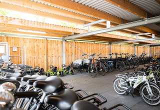 Overdekte fietsenstalling met veel fietsen en go-karts bij RCN de Schotsman vakantiepark in Zeeland.