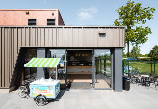 Ingang van een café met een ijskar buiten, moderne architectuur en zonnig bij RCN de Schotsman.