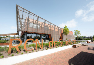 Modern gebouw aan RCN de Schotsman vakantiepark in Zeeland, Nederland, met duidelijk zichtbaar naambord.