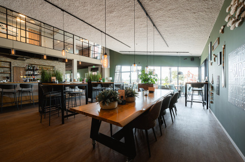 Restaurante moderno con mesas de madera y ventanales grandes en RCN de Schotsman, Zeeland, Países Bajos.