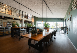 Modern restaurant met houten tafels, veel licht en planten bij RCN de Schotsman in Zeeland.