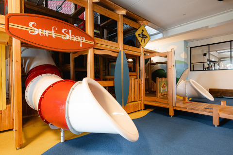 Parque infantil cubierto con temática de tienda de surf y toboganes en RCN de Schotsman, Zeeland, Países Bajos.