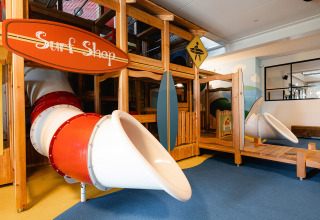 Overdekte speeltuin met surfshop-thema en glijbanen in RCN de Schotsman vakantiepark in Zeeland, Nederland.