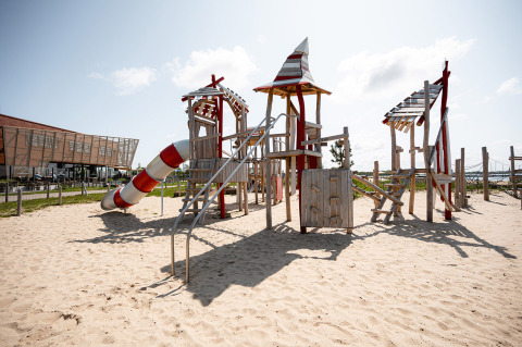 Parque infantil con estructura de madera y tobogán en arena en RCN de Schotsman, parque vacacional de Zelanda.