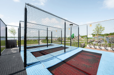 Zona de trampolines exteriores con red de seguridad en un parque vacacional con vistas en Zelanda.