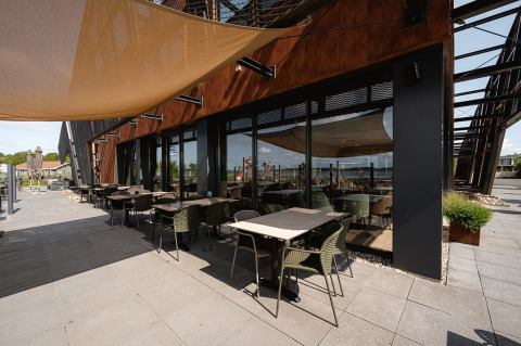 Outdoor seating area at RCN de Schotsman holiday park in Zeeland, Netherlands, with tables, chairs and sunshade.
