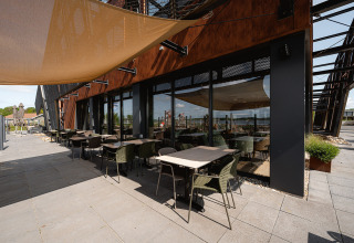 Buitenzitgedeelte bij RCN de Schotsman vakantiepark in Zeeland, Nederland, met tafels, stoelen en zonnescherm.