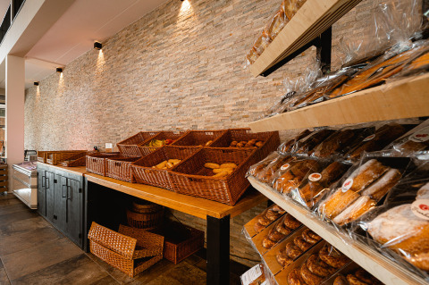 Sección de panadería con cestas y estanterías llenas de pan fresco en RCN de Schotsman en Zeeland, Países Bajos.