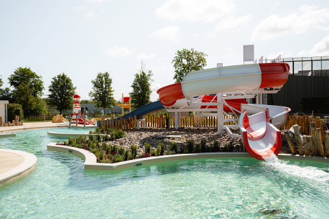 Waterpark met glijbanen en zwembad bij RCN de Schotsman, omringd door bomen in Zeeland, Nederland.