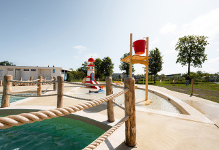 Waterspeeltuin met vuurtoren en emmer bij RCN de Schotsman vakantiepark in Zeeland, Nederland, zonnige dag.