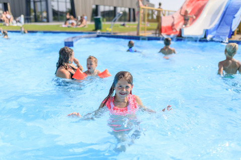 Niños jugando y nadando en la piscina exterior del parque vacacional RCN de Schotsman en Zelanda, Países Bajos.