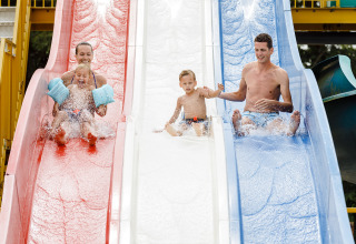Familie genießt Wasserrutschen im RCN de Schotsman Ferienpark, Zeeland, Niederlande, lachende Kinder und Eltern.