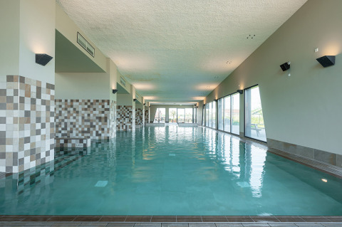 Piscina cubierta con grandes ventanales y diseño moderno de azulejos en RCN de Schotsman, Zeeland.