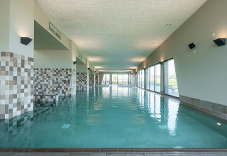 Indendørs swimmingpool med store vinduer og moderne flisedesign i ferieparken RCN de Schotsman, Zeeland.