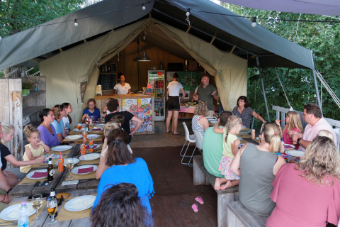 Familias y amigos se reúnen para compartir una comida en una carpa en Tenuta Tredici Ulivi, Marche, Italia.