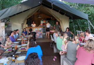 Gezinnen en vrienden genieten samen van een maaltijd in een tent bij Tenuta Tredici Ulivi in Marche, Italië.