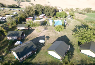 Luftfoto af Tenuta Tredici Ulivi feriepark i Marche, Italien, med telte, træer og swimmingpool.
