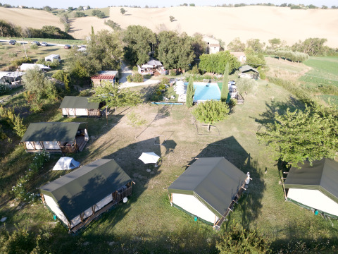 Vista aérea del parque vacacional Tenuta Tredici Ulivi en Marche, Italia, con tiendas y piscina.