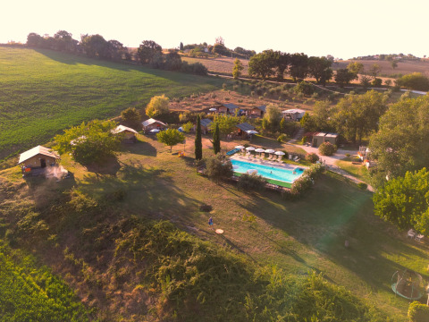 Vista aérea del parque vacacional Tenuta Tredici Ulivi en Marche, Italia, con piscina y campo verde.