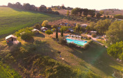 Luftfoto af Tenuta Tredici Ulivi feriepark i Marche, Italien, med swimmingpool og grønne marker.