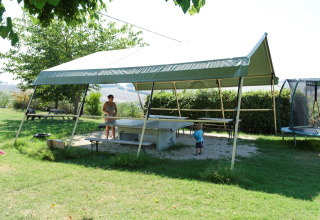 Buitenscène bij Tenuta Tredici Ulivi met tafeltennistafel, overkapping en mensen die van de zon genieten.